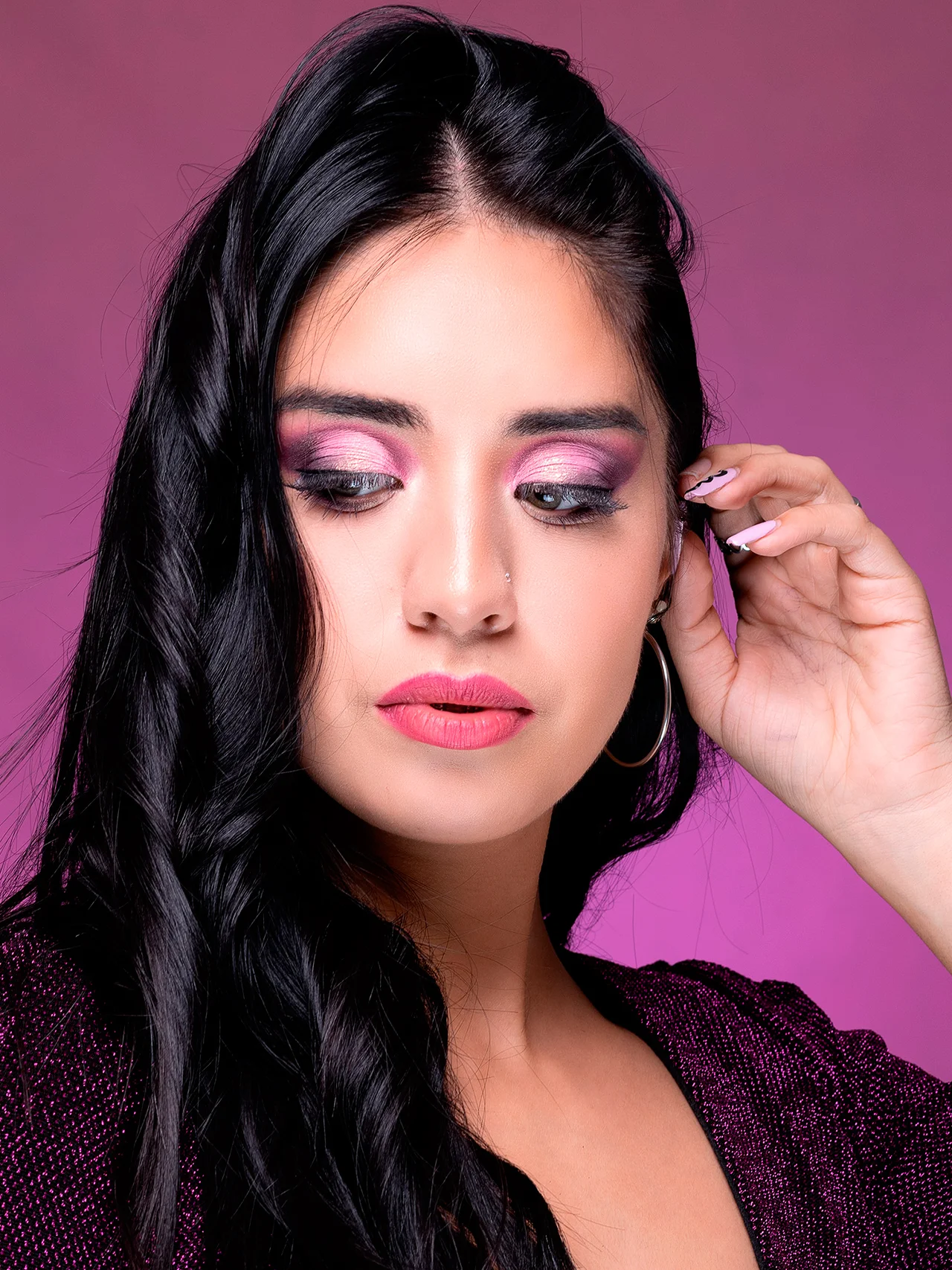 Peinado de ondas glamorosas en cabello largo de color negro intenso con un acabado brillante y sedoso para el sitio de Meli Figarola. El look destaca una melena saludable y estilizada en un primer plano editorial, complementado con un maquillaje artístico en tonos rosados y un fondo vibrante.
